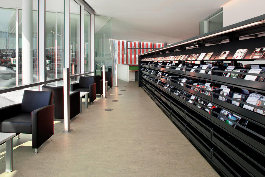 &#193;rea de lectura moderna con estantes de revistas en una biblioteca.