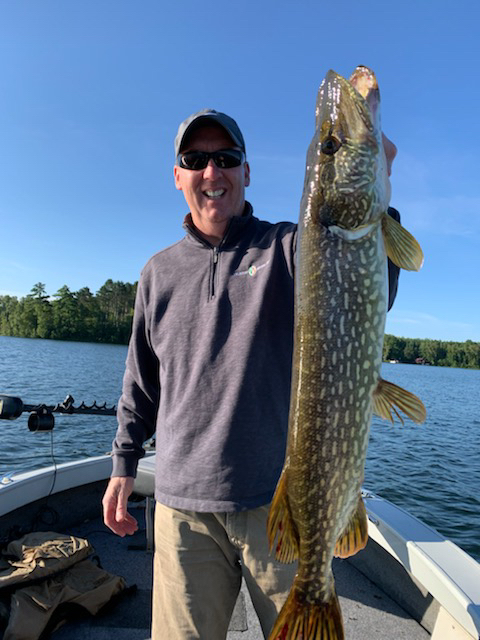 Man holding a large fish caught in a lake.