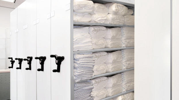 Estanter&#237;as compactas para almacenamiento de ropa doblada en entornos de salud.