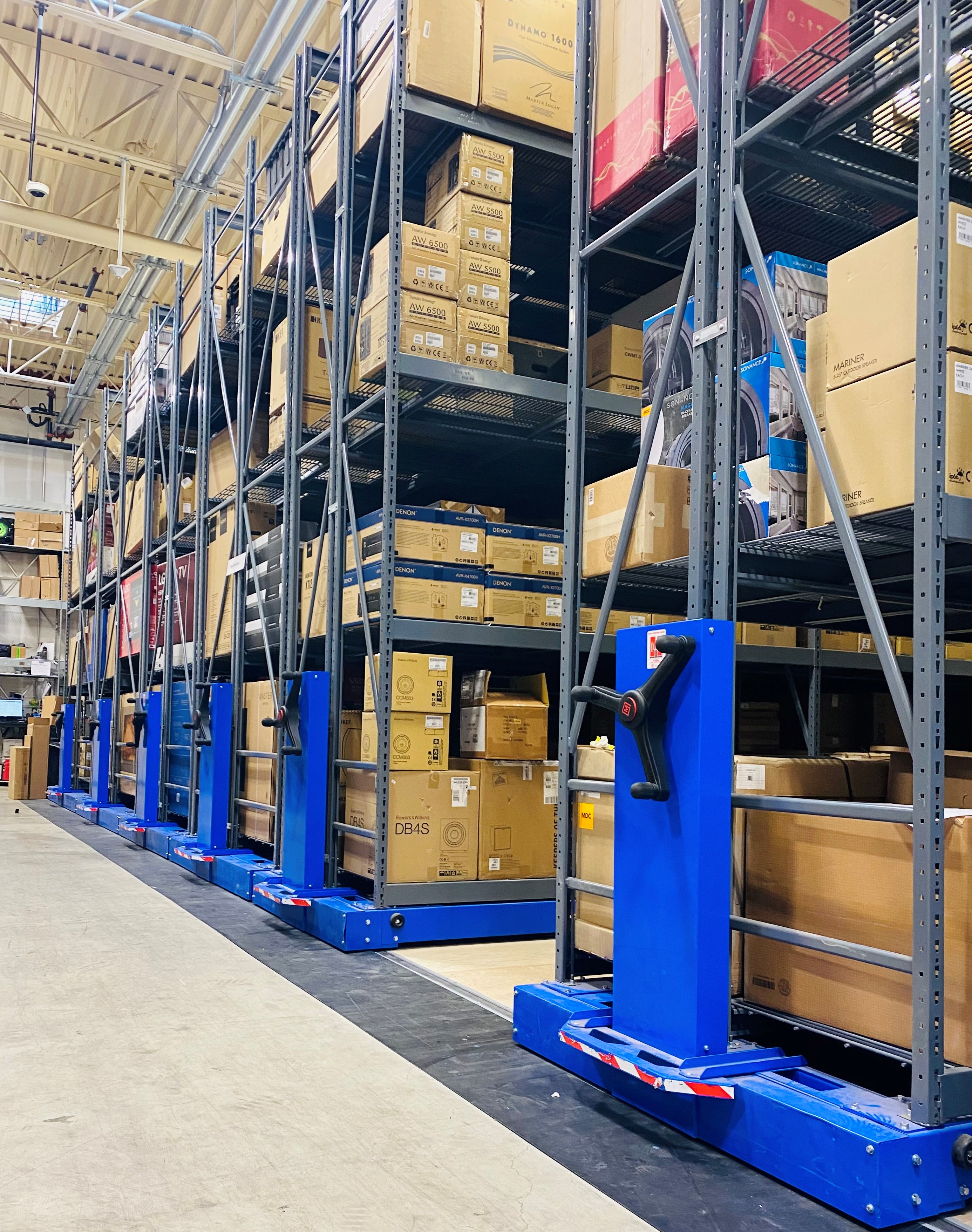 Sistema de estanter&#237;as m&#243;viles Montel con estantes industriales y manivelas azules, utilizado para el almacenamiento de cajas en almac&#233;n.