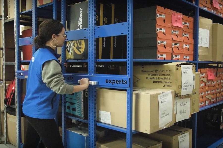 Trabajadora manipulando art&#237;culos en estanter&#237;as azules.
