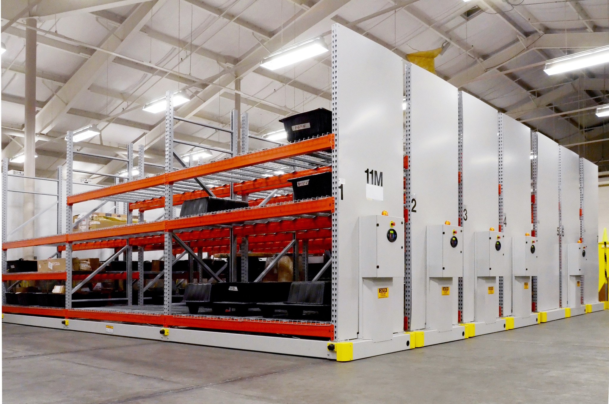 Sistema de estanter&#237;as Montel en un almac&#233;n con estantes naranjas y paneles de control electr&#243;nicos.