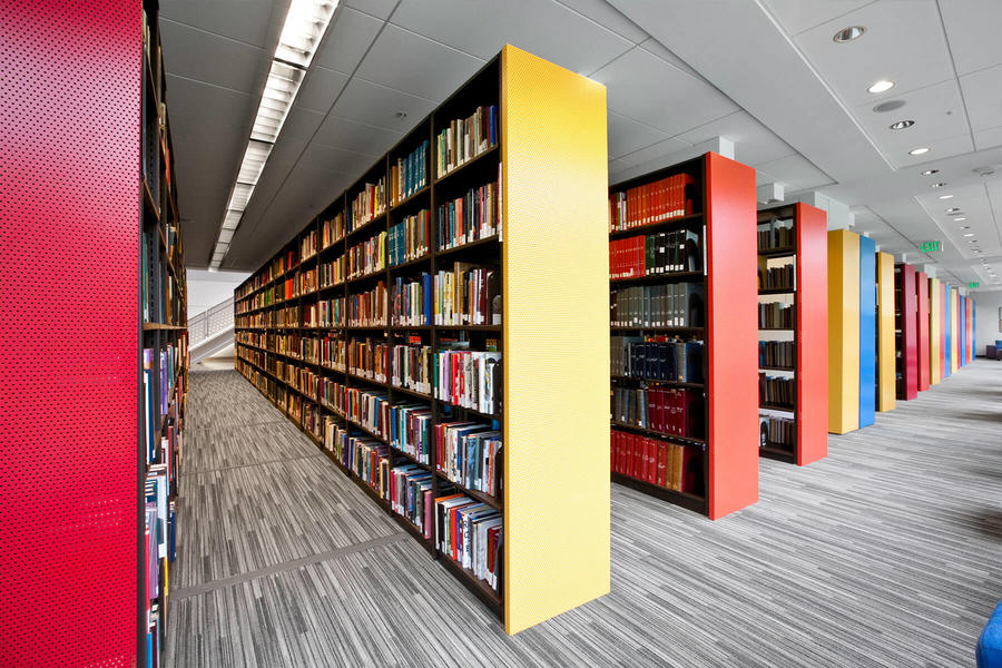 Sala de estudio en una biblioteca con asientos verdes y estantes llenos de libros.