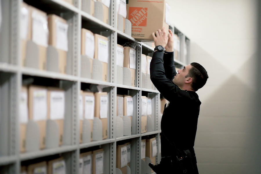Oficial organizando archivos en estanter&#237;as de archivo.