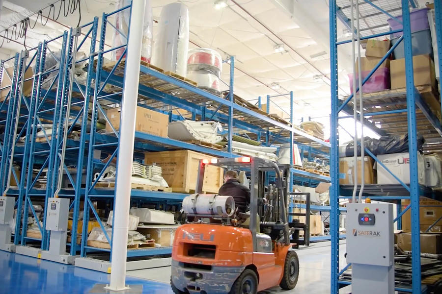 Montacargas transportando piezas en un almac&#233;n con estanter&#237;as azules