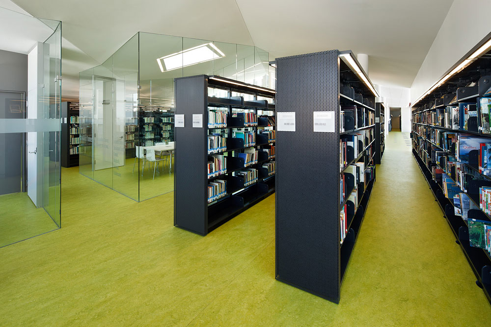 Fila de estantes negros en una biblioteca moderna con suelo verde.