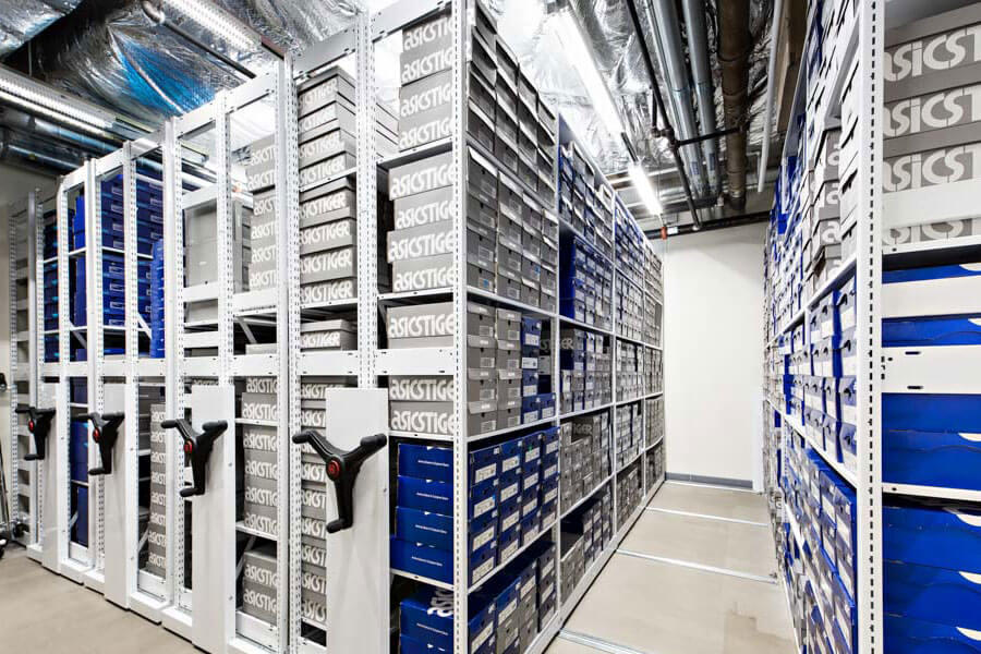 Montel mobile shelving system in an Asics shoe warehouse, optimizing shoe box storage with black hand cranks.
