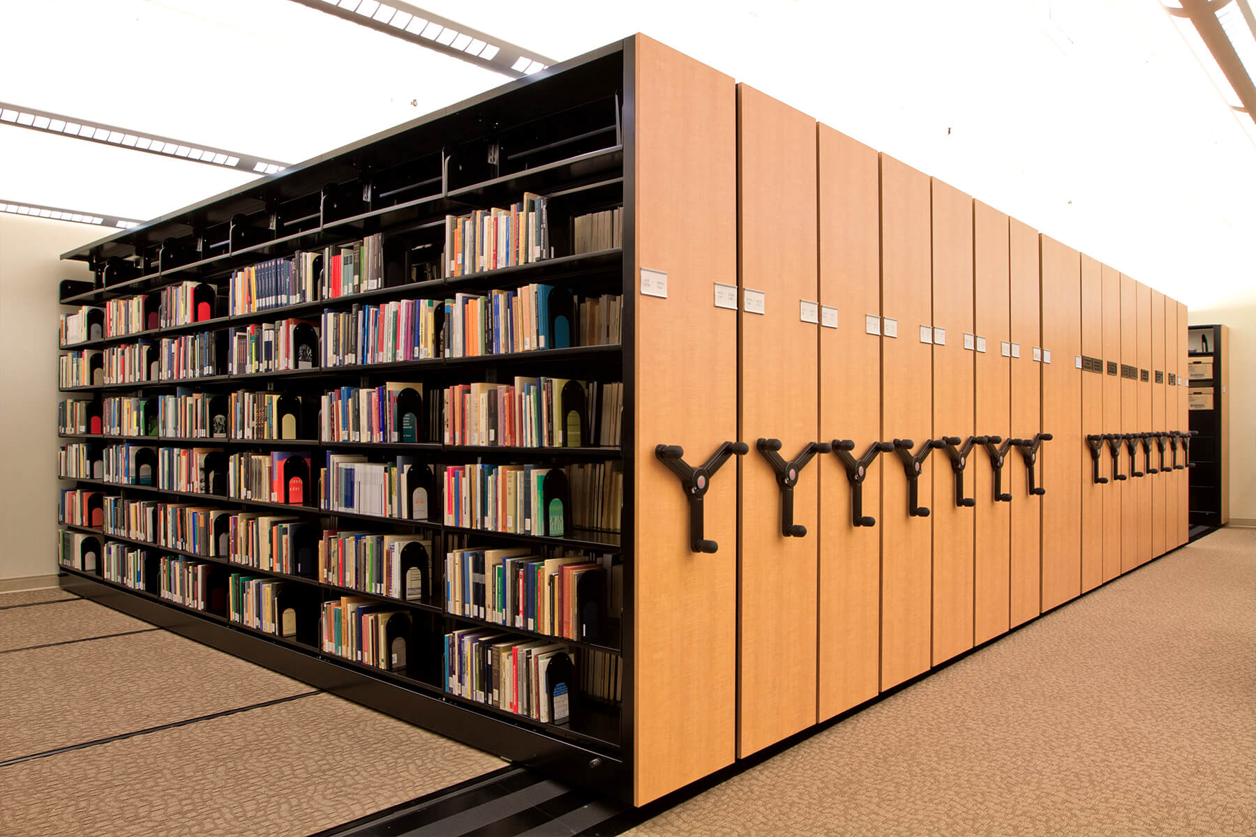 Estanter&#237;as de biblioteca m&#243;viles con paneles de madera clara para optimizaci&#243;n del espacio.