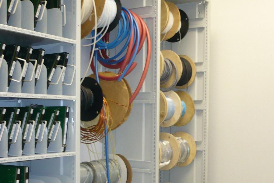 Carretes de cables de colores y placas electr&#243;nicas en una estanter&#237;a.