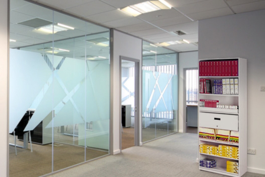 Oficinas modernas con divisiones de vidrio en un espacio de trabajo abierto.